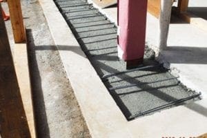 Worker puts first level of concrete between two supporting posts in earthquake retrofitting process 20